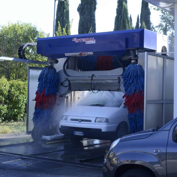 Aggiunta di un'auto nel lavaggio automatico con spazzole rotanti blu e rosse.