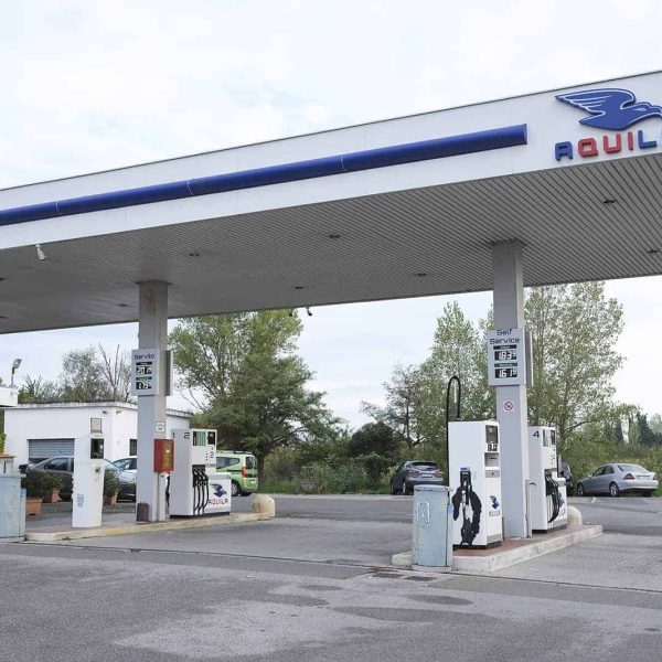 Stazione di rifornimento carburante Aquila Energie con pompe e veicoli in attesa.