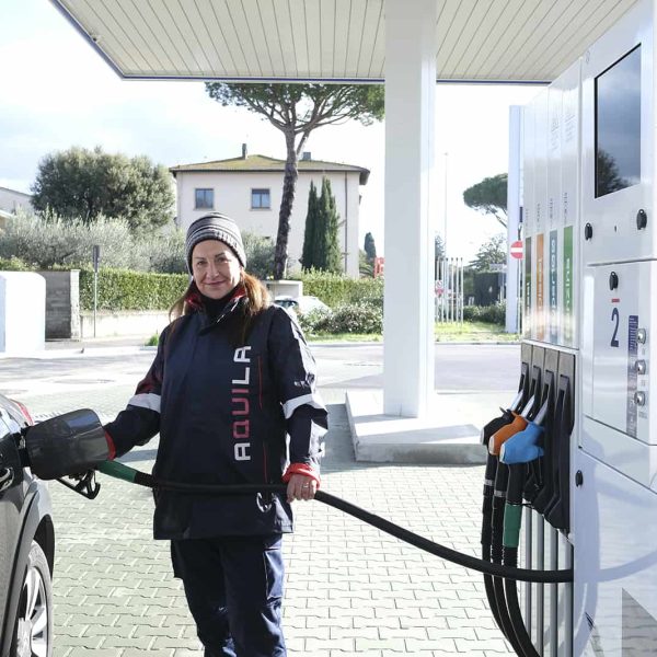 Persona che rifornisce un'auto presso una stazione di rifornimento di energia elettrica.