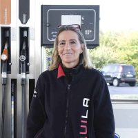 Pompa di carburante con operatrice, energia sostenibile e servizi di rifornimento.