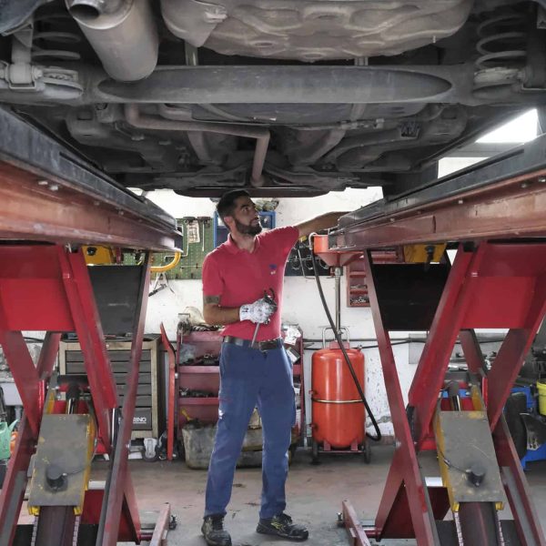 Sicurezza e manutenzione auto sotto il veicolo su ponte sollevatore in officina.