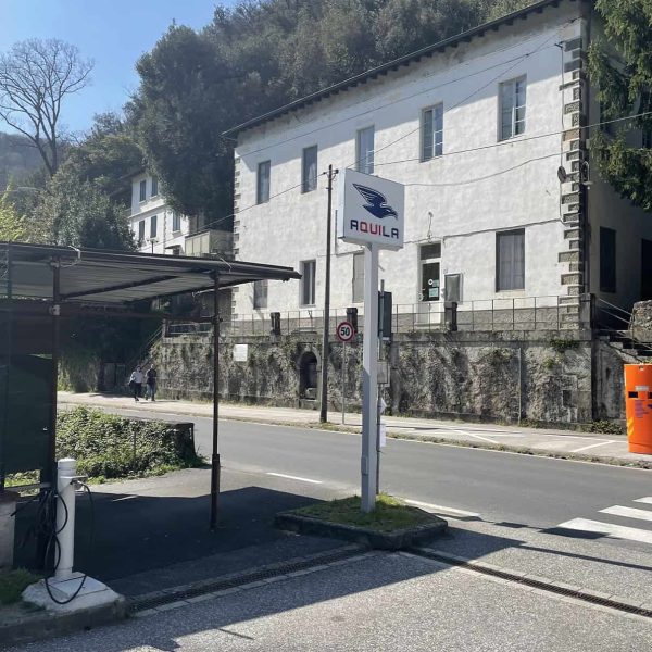Aquila Energie edificio con logo aziendale in zona urbana e colline sullo sfondo.