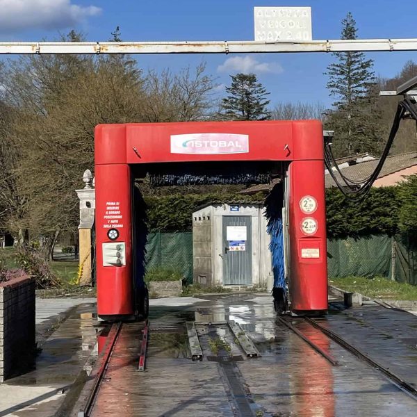 Stazione di ricarica veicoli elettrici all'aperto con arco rosso e pannello solare in background.